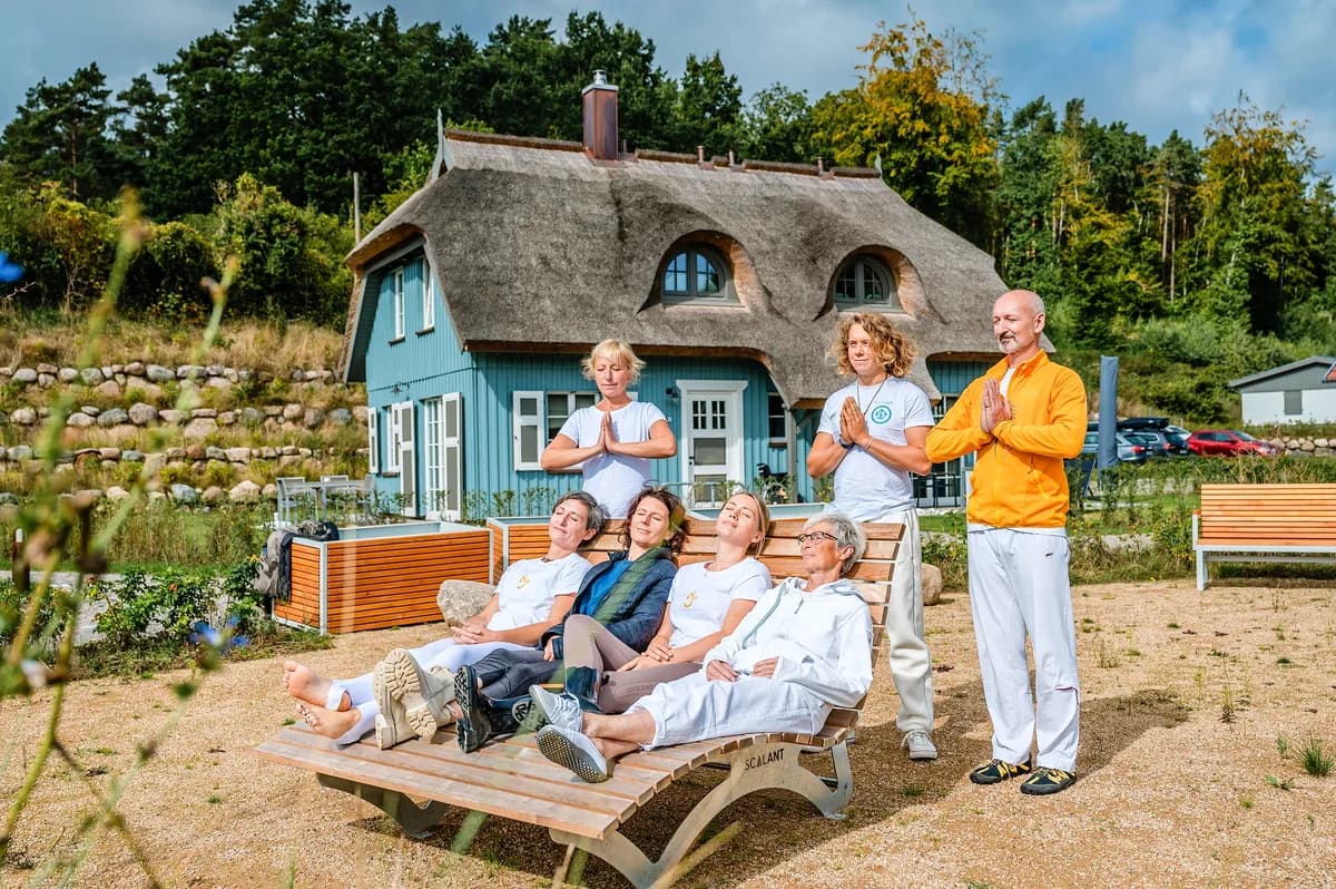 Fastengruppe bei einer Meditation vor einem reetgedeckten Ferienhaus in Klein Stresow