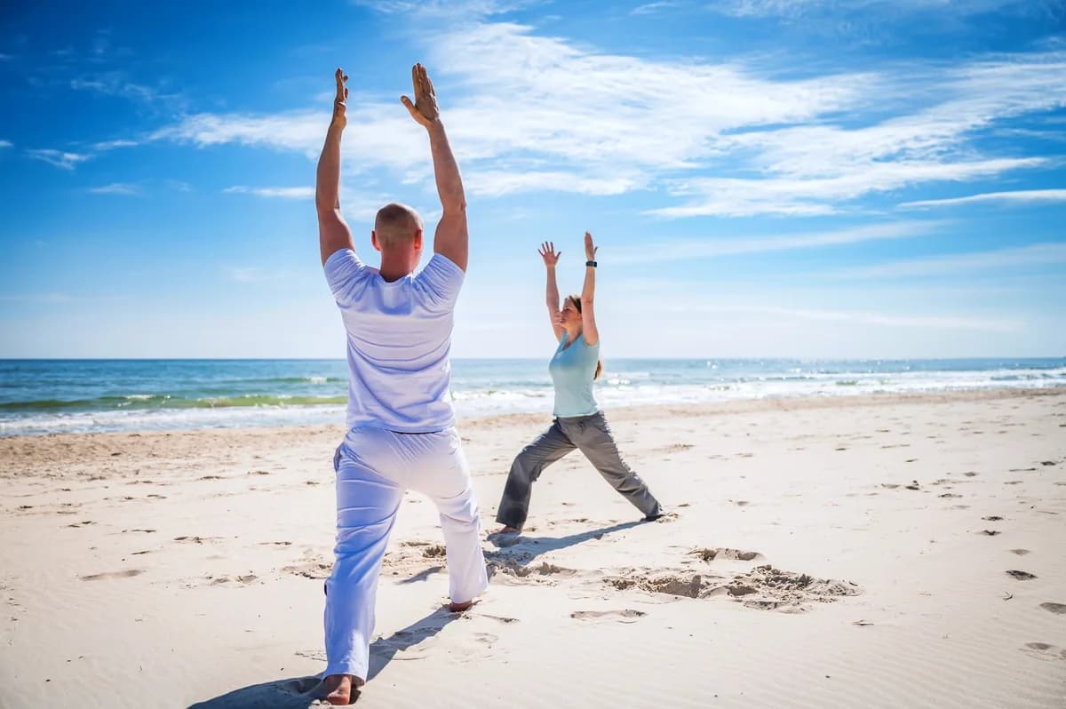 Zwei Menschen bei einer Yoga-Übung am Ostseestrand